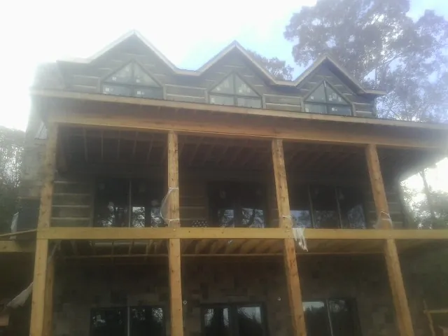 Dormers and porch framing on a large log home under construction — Roof Coating work by our crew in Emery