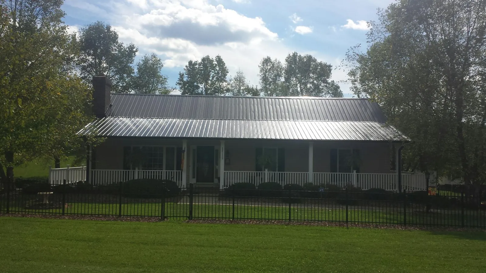 Gray metal roof on a brick ranch with a full width front porch — Gutter Guard Installation work by our crew in Emery