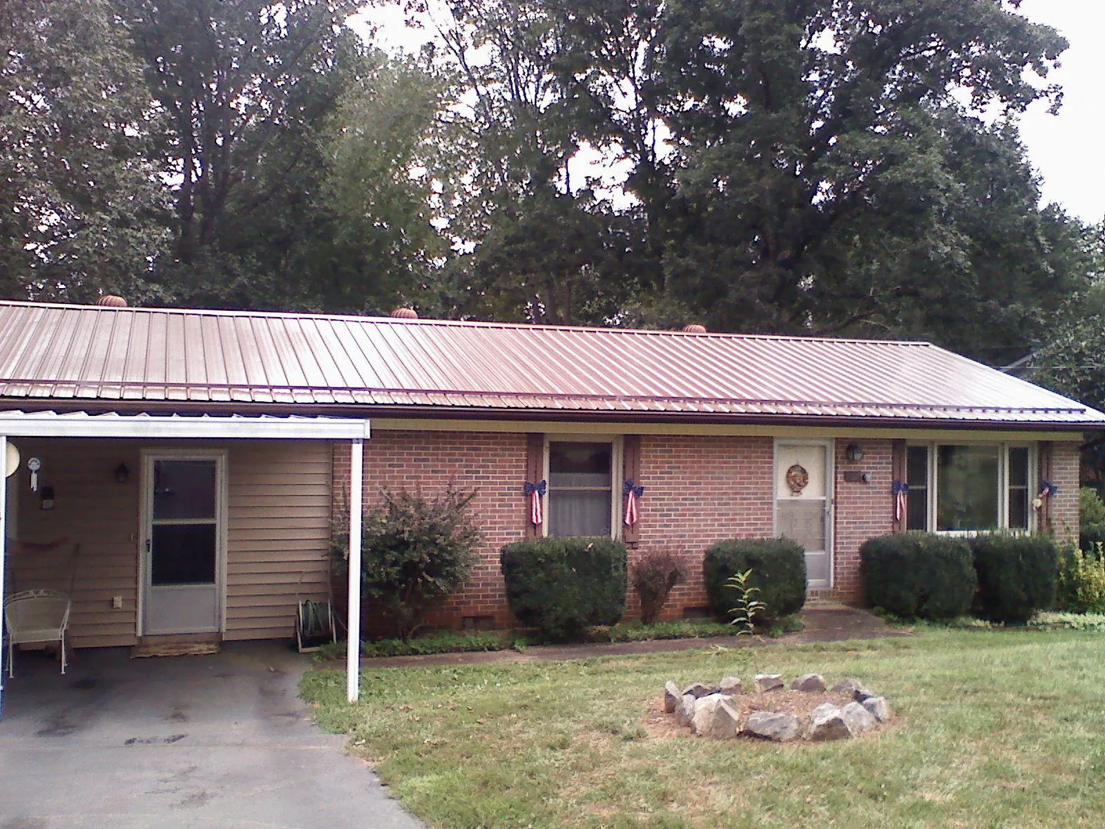 Bronze metal roof and carport on a brick ranch home — Roof Repair work by our crew in Emery