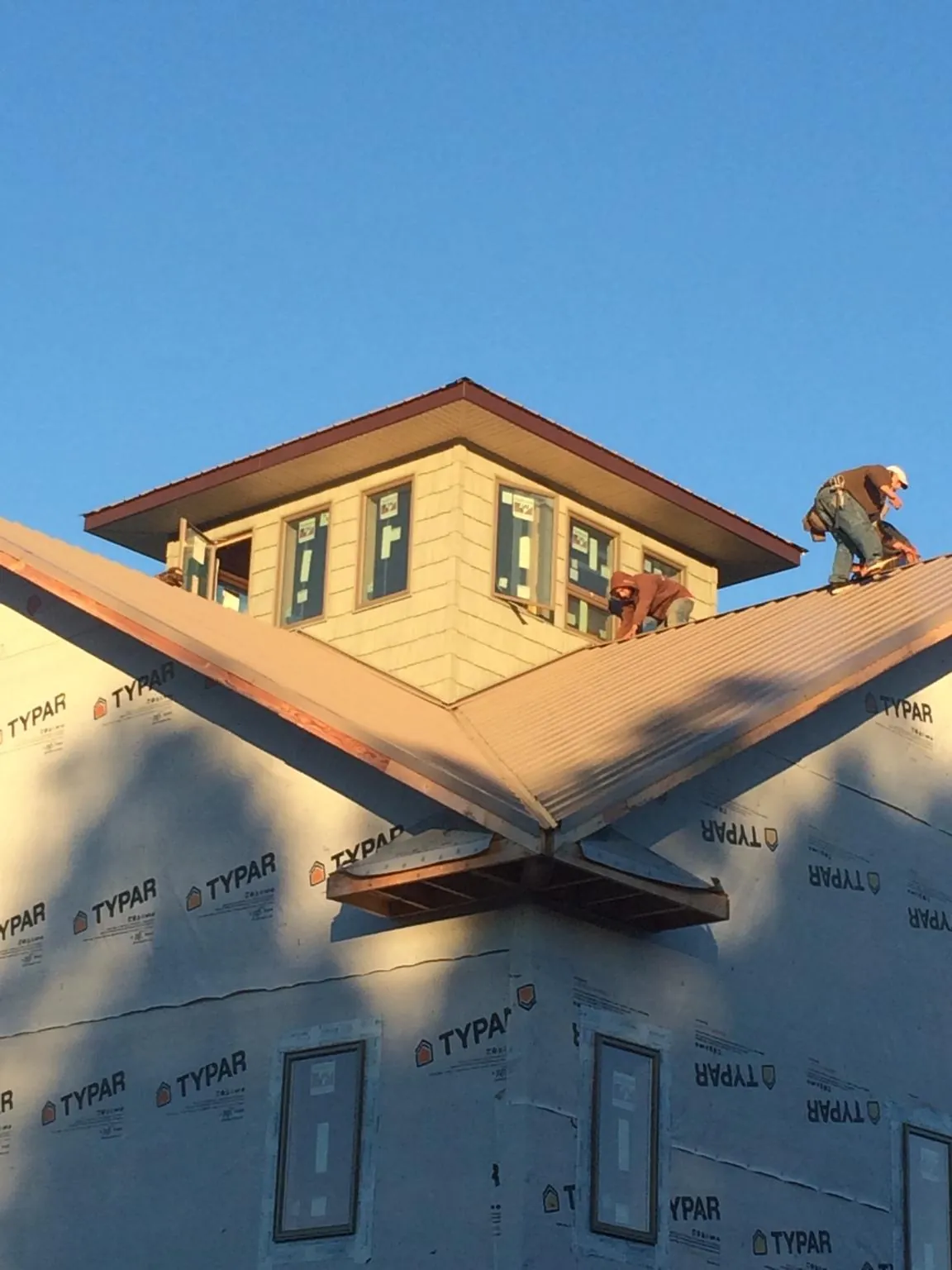 Roofers working around a rooftop cupola on a new metal roof at sunset — Roof Waterproofing in Emery by Roofing Brothers